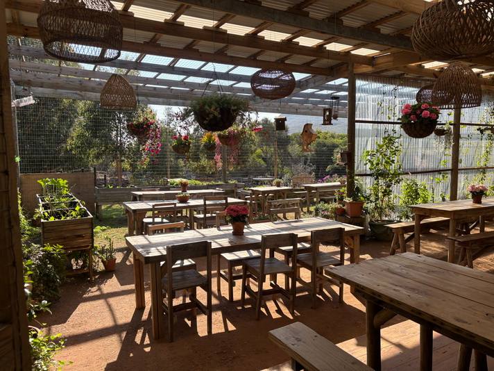 Wooden harvest tables under the shaded pergola at the Cape Point farm